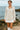 Female walking on seaside rocks in Fitted Linen Blend Shirt with Ribbon Embroidery Color: OATMEAL, cloudy sky.