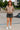 Woman posing in cocoa fleece cropped zip hoodie with black denim mini skirt and white sneakers, skatepark afternoon.