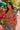 Woman in a floral blouse holding flowers at a sunny farmers market