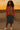 Woman in a floral blouse and denim skirt at sunset on a rooftop