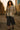 Walking on urban alley in floral-patch denim jacket, navy culottes and combat boots, sunset glow