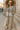 Standing on museum steps in floral-patch denim jacket with culottes and strappy sandals, morning sun
