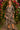 Woman standing in Floral Print Tiered Midi Dress with black heels, under flower arch, evening lights