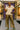 Woman in a beige top and gold pants standing on a runway with a purple 'Xtara' banner in the background.