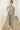 Woman in melange gray lounge set walking with a mug through a hallway