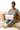 Woman in gray lounge set working on a laptop on the couch with a candle