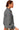 Side view of charcoal ribbed sweater with ribbed knit texture and raglan sleeve shape.