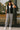 Woman standing in Heart Quilted Vest with joggers and sneakers, holding cap, outside coffee shop