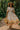Woman in ivory printed midi dress walking through a tropical garden path