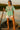 Woman in mint lace babydoll blouse with white shorts and wedges on boat at sunset