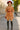 White model in full-body boho dress with red hat and boots on Paris street
