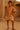 South Asian model in boho tassel dress with rope belt, bike shorts, and sandals in desert adobe setting