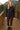 Woman in midnight eyelet cardigan with gold buttons, brown leggings and fur boots, standing on cabin deck