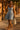 Woman in a denim dress walking on a sidewalk with a brick wall background