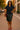 Smiling woman standing in navy lace short sleeve shirt with leather skirt and red heels, city sunset