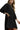 Black dress with gold trim worn by a model on a white background
