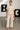 Woman in beige slub lounge set with silver sandals in art gallery
