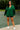 Front view of model in green hoodie and black sport shorts on tennis court background
