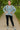 Woman in Oversized Sweater with Side Slit, black leggings and gray sneakers, standing on path with green trees
