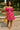Standing by fountain in paisley off-shoulder dress with apple basket and nude flats, summer park