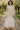  Woman standing in Patchwork Floral Button-Up Shirt with cream maxi skirt and flats, in orchard, daylight