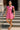 Smiling on museum steps in pink mini polo dress with loafers and shoulder bag, sunny midday