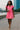 Walking with coffee in pink mini polo dress and sandals, riverside walkway, morning light