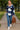 Model walking on park path in oversized plaid fleece shacket with jeans and white sneakers, daytime