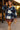 Woman posing in oversized plaid fleece shacket with leather skirt and boots, terrace at sunset