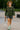 Woman in plaid ruffle collar blouse with gray cargo shorts, hat and sneakers, city street daylight.