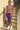 Woman in a colorful plaid top and purple skirt standing on steps.