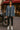  Woman in raw hem denim jacket with tassel drawstrings styled with leather leggings and white sneakers