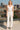 Woman in white ribbed tank top and high-waisted jeans with heels on urban rooftop