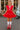 Woman in a red dress and roller skates standing on a street.