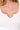 Close-up of a person wearing a white ribbed top with a scoop neckline.