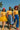 Three women wearing yellow striped knit tops styled with bold skirts and pants