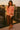 Woman in a striped sweater and brown skirt standing on a rooftop with cityscape background