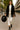 Woman in black fringe blazer, white blouse, white pants, black boots, holding hat, Paris daytime