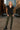 Standing in black ribbed sweater vest with camo cargo pants and lace-up boots, downtown urban backdrop