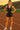 Woman standing in Tie-Front Sleeveless Romper with white sneakers, on running track, sunset light