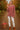 Woman holding apple in dark red turtleneck sweater, with suede boots, orchard daylight