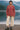 Woman on dock in dark red turtleneck sweater, with sneakers, misty lake morning light