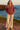 Woman standing on cliff in dark red turtleneck sweater, with espadrilles, sunset glow