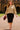 Model walking in Wide Neck Band Drop Shoulder Sweater with black skirt and heels, campus courtyard sun.
